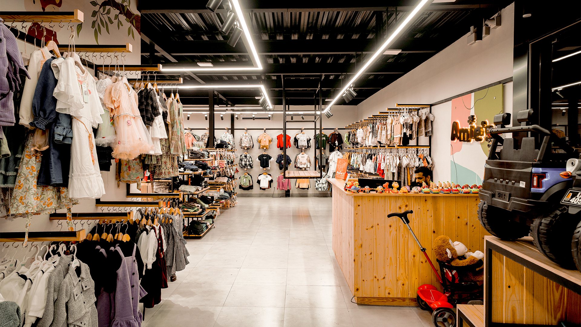 Central shop aisle framed by clothing racks, a wood counter and angular ceiling lights