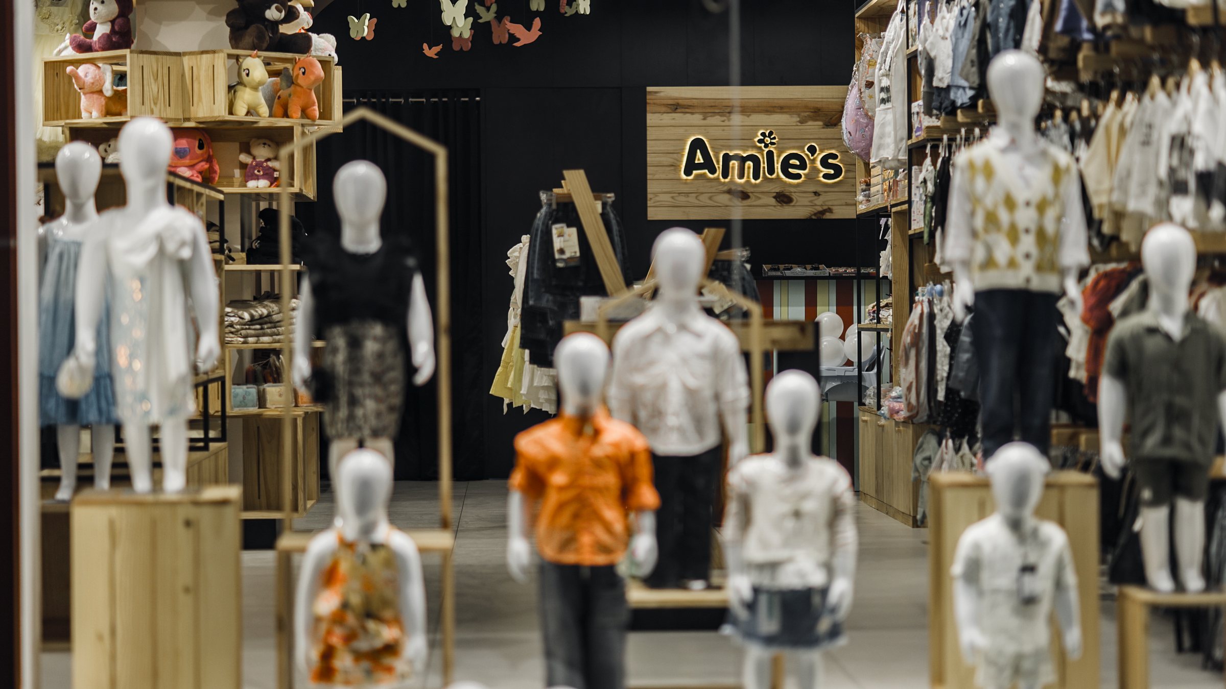 Children's mannequins in shallow focus with the Amie's sign centered at the rear
