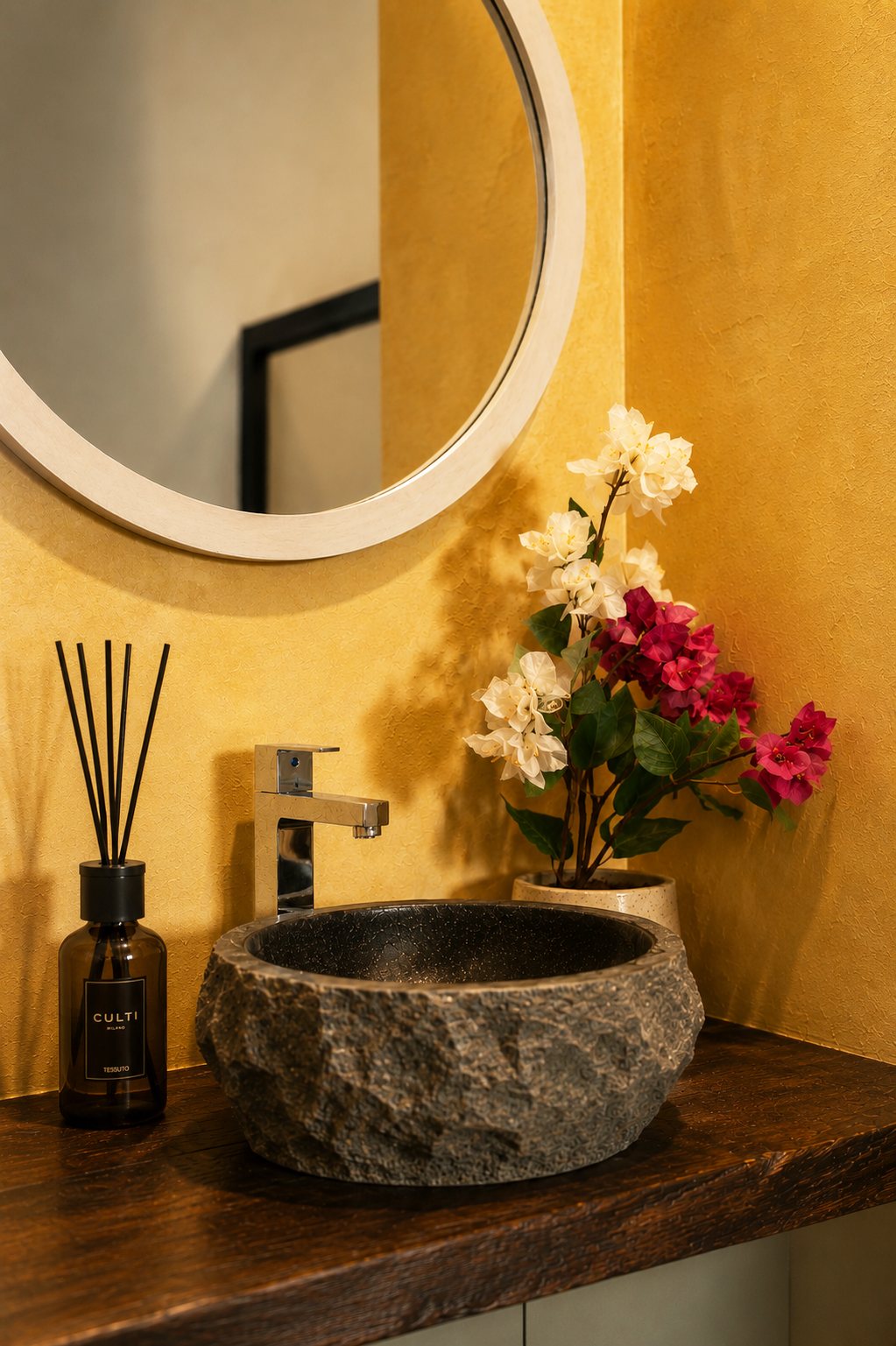 Stone vessel basin on a dark wood counter against a warmly lit ochre wall