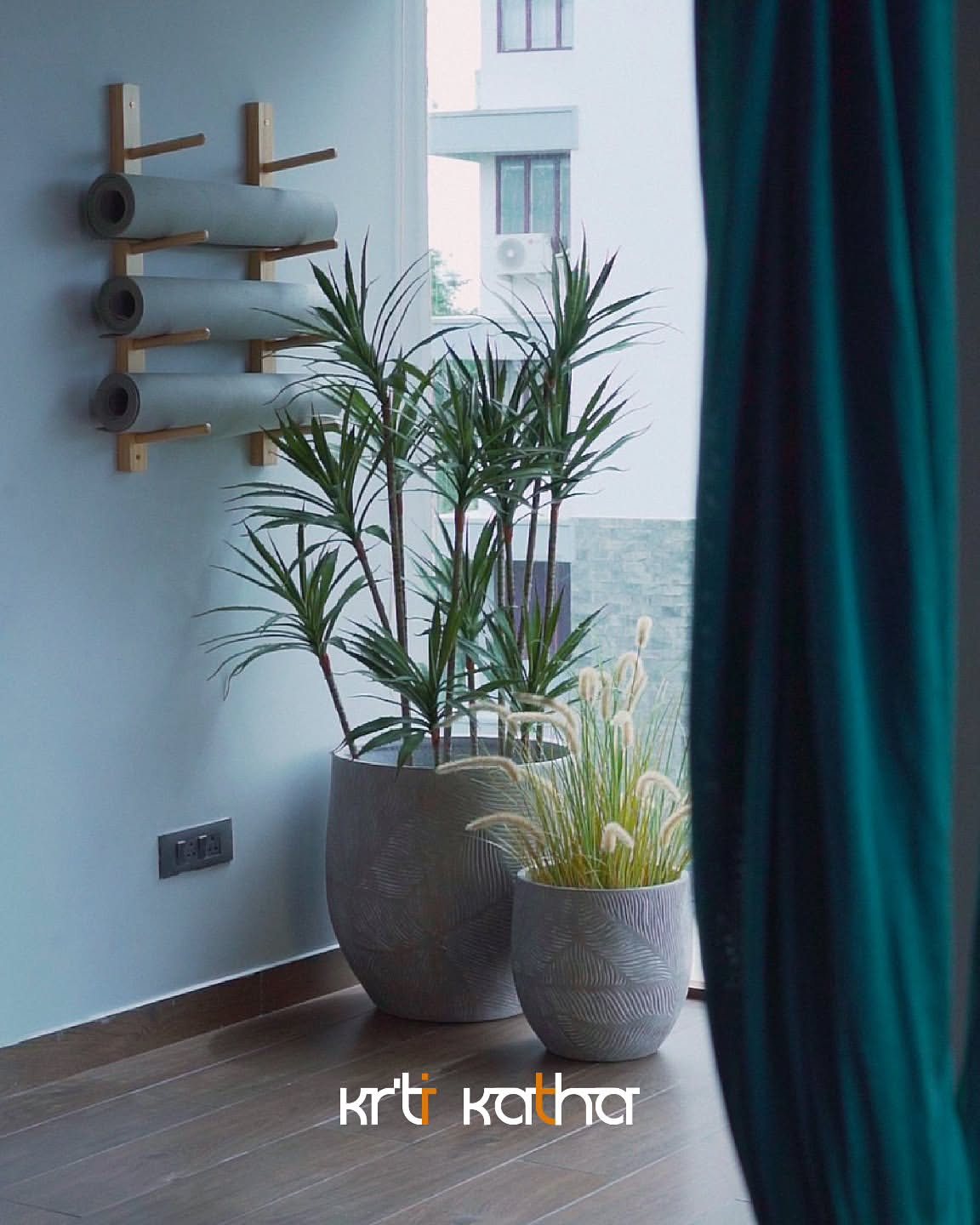 Yoga studio corner with potted palms, wall-mounted mat storage and a teal curtain
