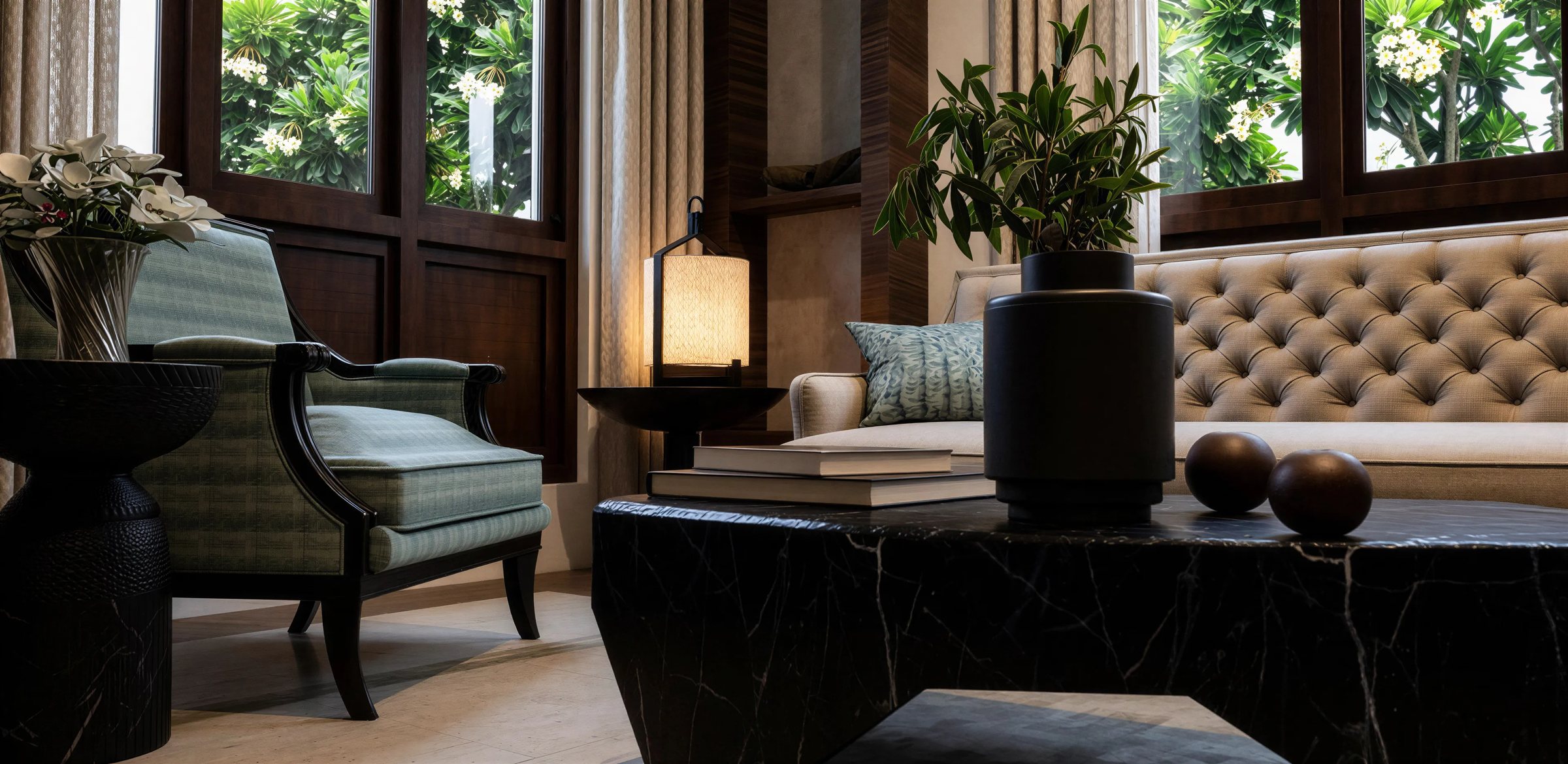 Sitting room with tufted cream sofas, a blue armchair and faceted black stone tables